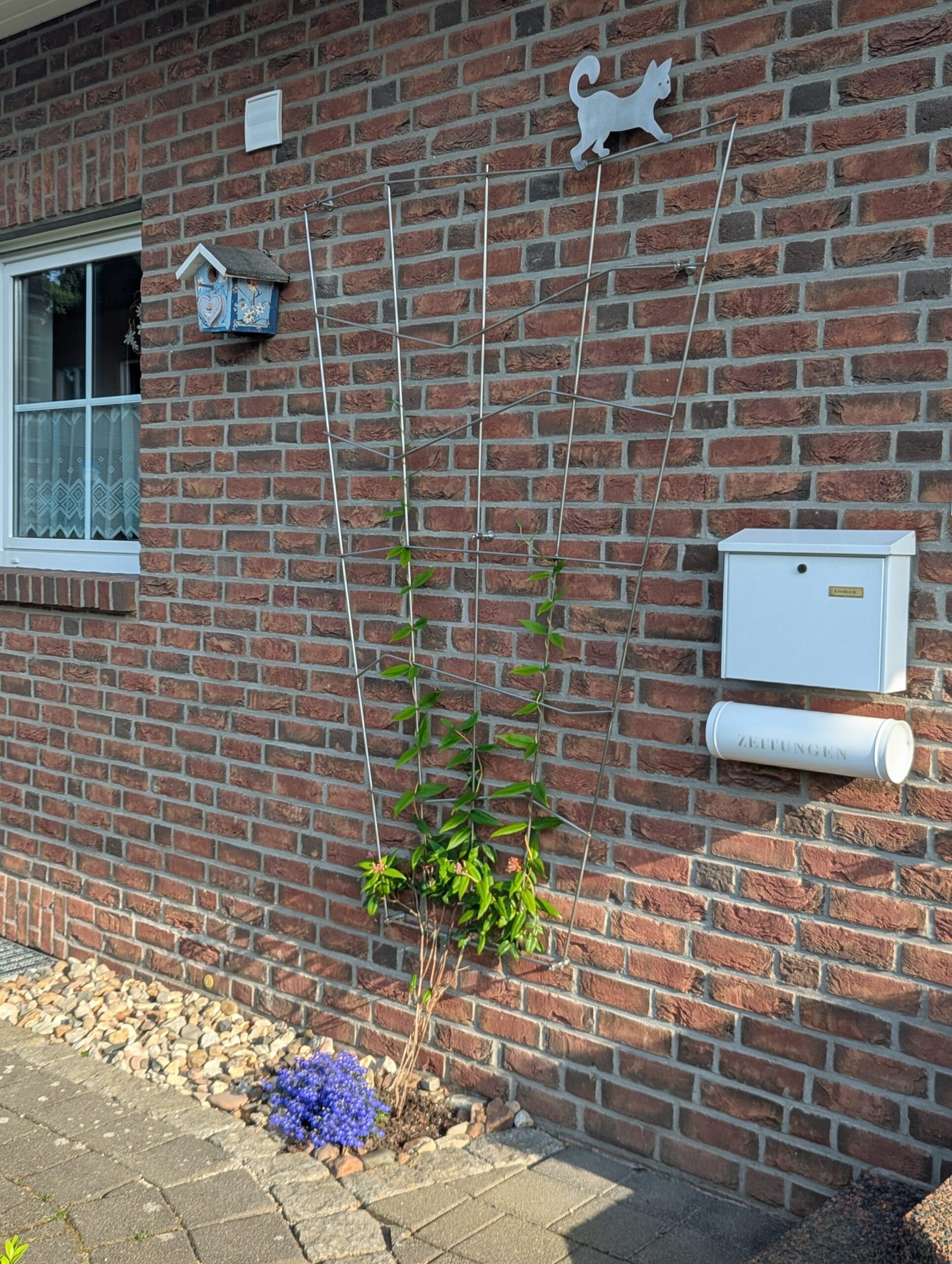 Edelstahl-Rankgitter mit Katzen-Motiv an Klinkerfassade